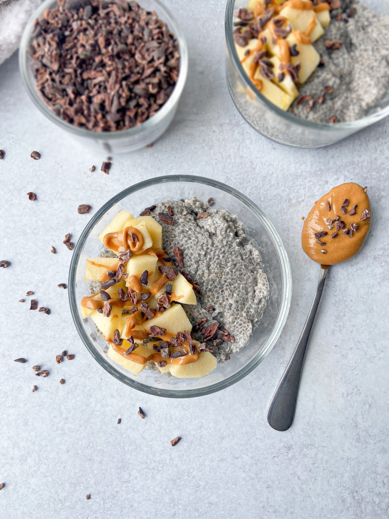 Chia seed pudding topped with peanut butter, apples and cacao nibs